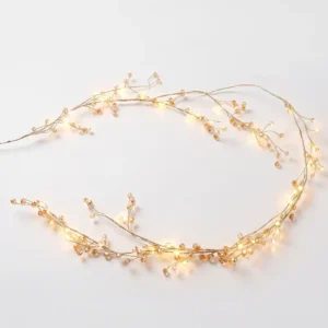 Instalación navideña dorada con luces cálidas y ramas decorativas